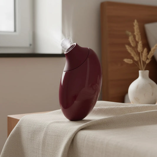 Elegant Crimson Pebble silent massager on a bedside table, displaying powerful touchless air-pulse technology