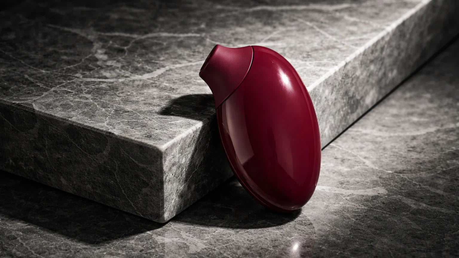 A severely close-up, high-end editorial shot of flawlessly smooth, heavy medical-grade silicone used exclusively in premium luxury wellness tools, resting boldly on cold marble.