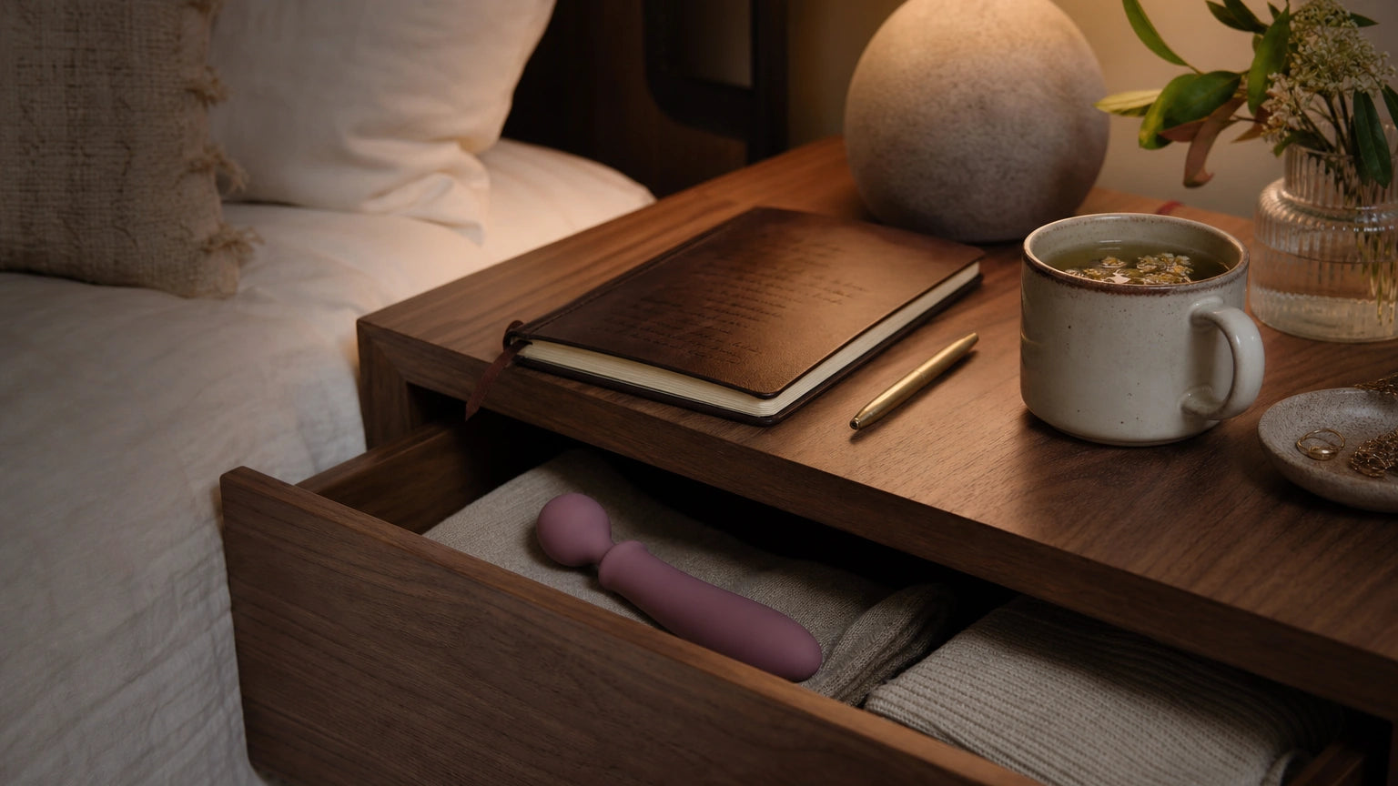 Silicone massager stored near a planner, tea, and bedside notes about sleep support