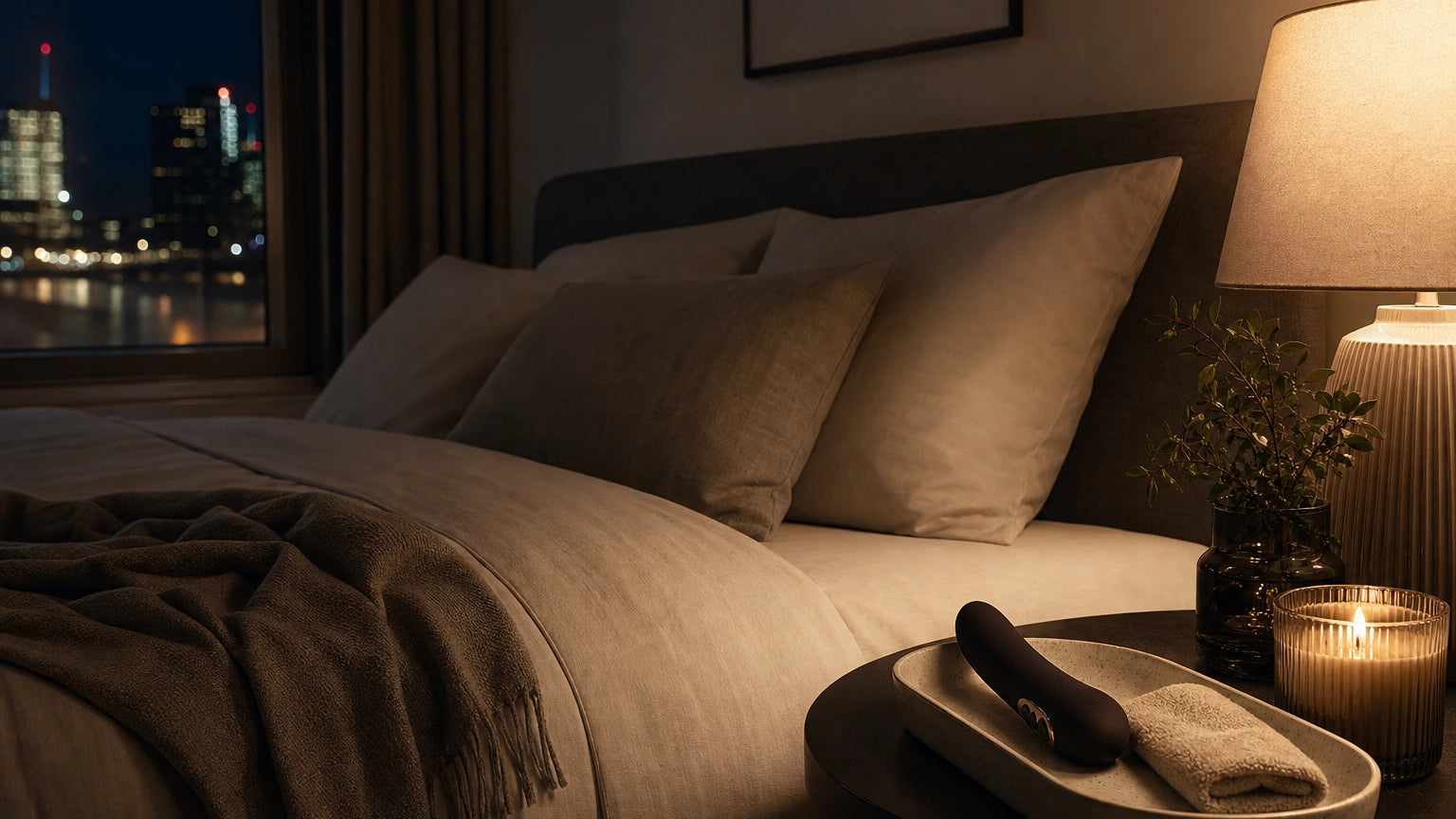 Body-safe vibrator arranged on a bedside tray with a candle and towel as part of a 15-minute evening self-care routine