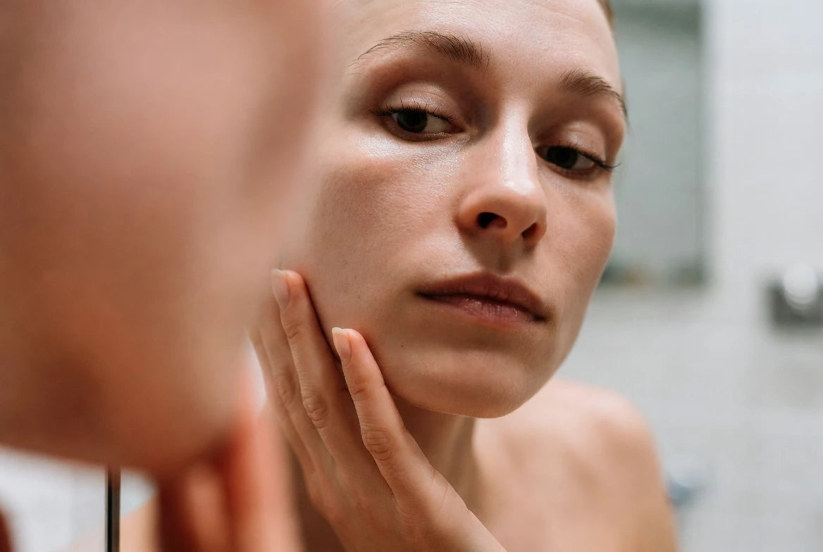Close-up of a person checking cheek and jawline puffiness in a bathroom mirror