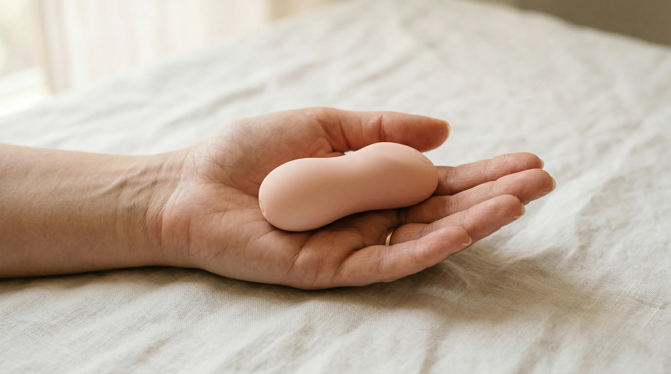 First vibrator shown at human scale — compact silicone design sitting comfortably in palm